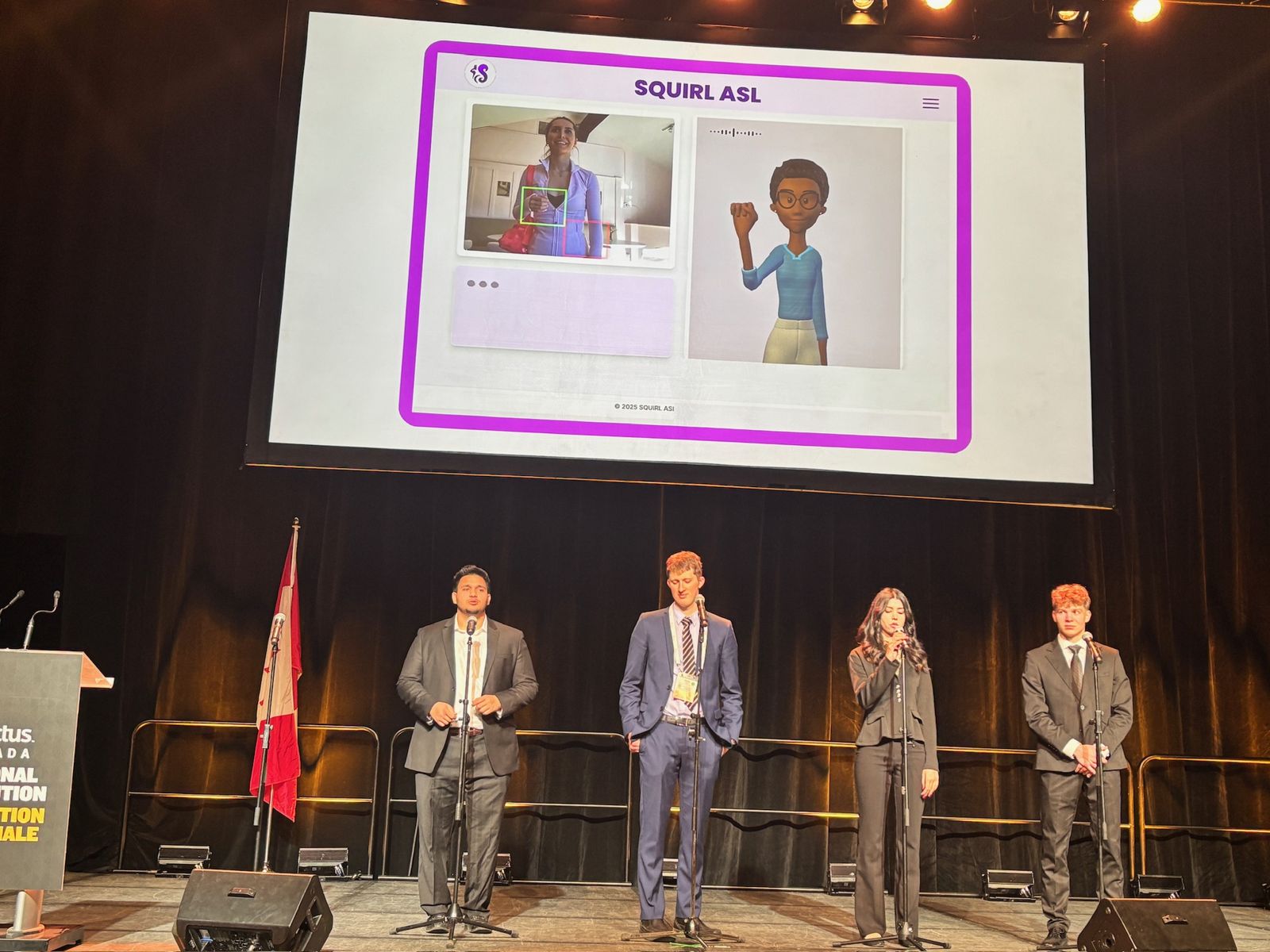 The Squirl Signs team presenting on stage, with the app on the screen behind them